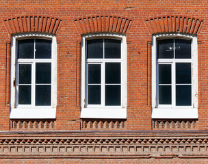 Three windows on a brick wall with white frames