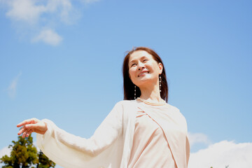 青空の下で手を広げリラックスする笑顔のシニア女性