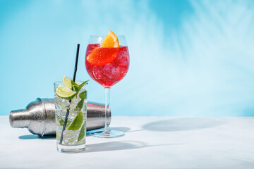 A variety of cocktails and cocktail shaker arranged on a table against a light blue background