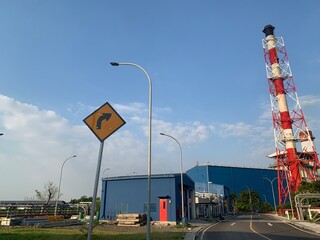Industrial Facility with Red and White Chimney. A view of an industrial facility with a red and...
