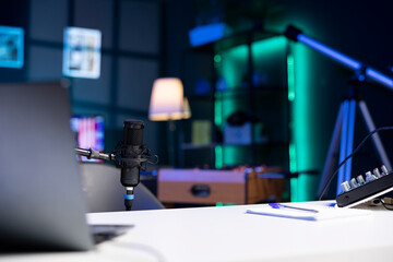 Close up shot of professional microphone in empty studio illuminated with rgb lights at night, used for internet video production. Content creation recording mic in apartment