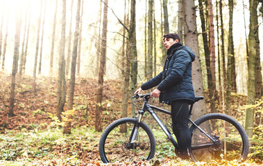 Obraz premium Young man resting by bike in the middle of beautiful forest. Concept of healthy lifestyle.