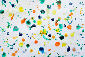 Drops of paints of different colors, on a white sheet of paper, artist's studio. Background for your creative design or addition to illustrations.
