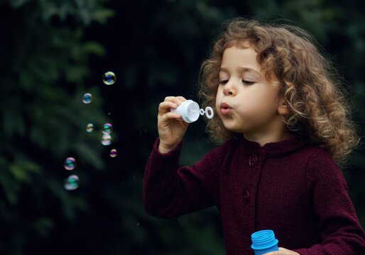 Little girl blowing bubbles in a park: joyful playtime and childhood fun outdoors
