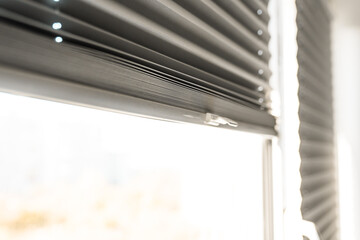 Gray roller blind on window indoors, closeup.