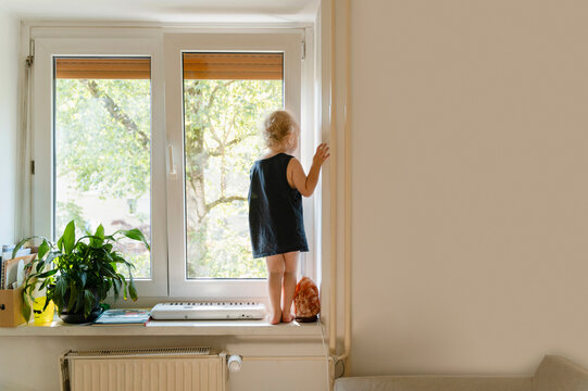 Boy in undershirt standing in front of window at home