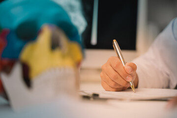In the laboratory, the doctor, a dedicated lecturer in anatomy, was examining the human skull closely, taking detailed notes to enhance his students' education on cranial structure.