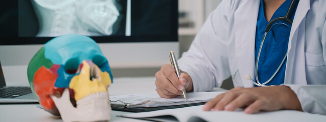 banner background of the doctor, a dedicated lecturer in anatomy, was examining the human skull closely, taking detailed notes to enhance his students' education on cranial structure.
