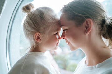 Happy mother embracing daughter near window