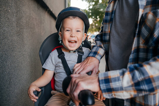 Father fastening seat belt of son sitting on cycle
