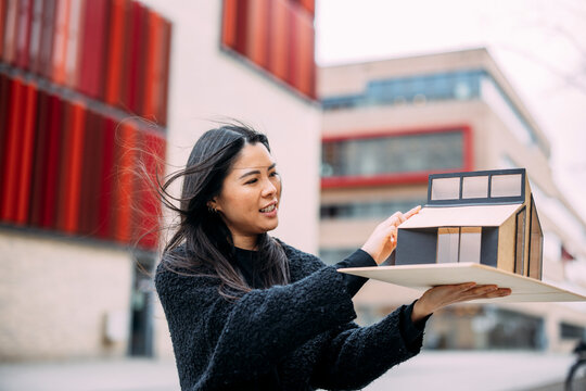 Architect examining house model outside office building