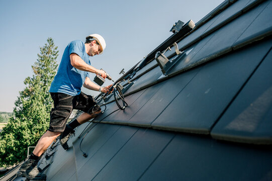 Engineer using drill machine and installing brackets on rooftop