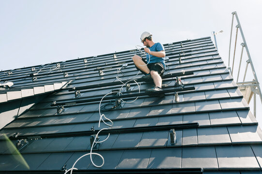 Engineer installing cable on rooftop under sky