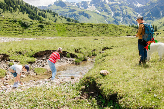 Father standing near children playing in water on meadow