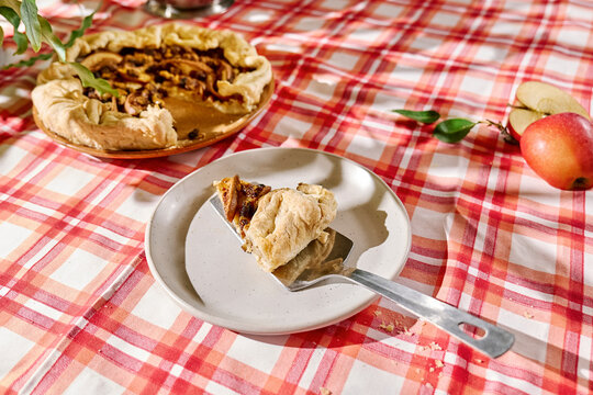 Slice of apple pie on plate over red table cloth