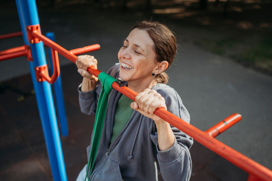 Cheerful mature woman exercising on horizontal bar