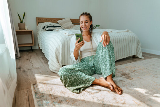 Happy woman using smart phone in bedroom at home