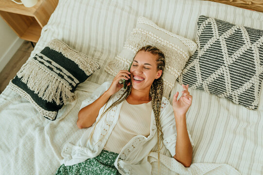 Happy young woman talking on mobile phone and relaxing at home