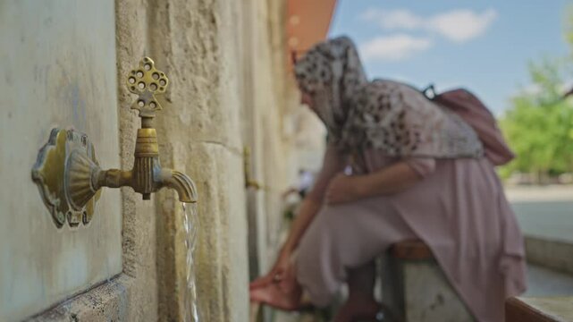 Water Flowing from the Vintage Outdoor Faucet While Muslim Woman in Hijab Performs Washing Ritual in Turkey. Concept of Ablution, Islam, Cleanliness, Spirituality, Religion, Purification, Refreshment