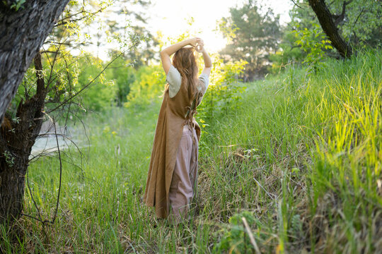 Young woman standing with hands raised in green forest - Powered by Adobe