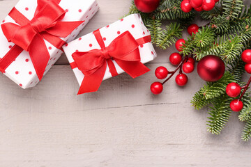 Christmas tree branches with balls, rowan and gift boxes on grey wooden background