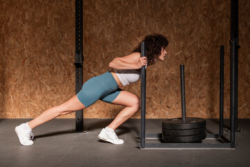 Athletic woman doing sled training at gym