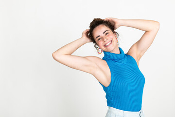 Happy beautiful woman with hands in hair standing against white background