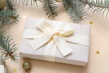 Christmas tree branches and gift box on beige background