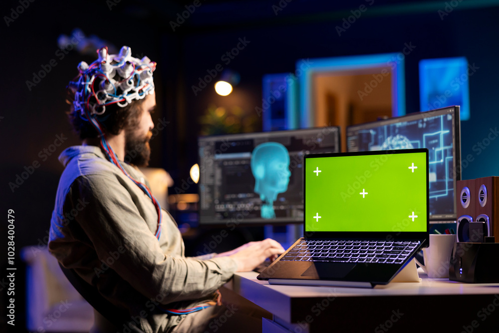 Poster focus on green screen laptop with man in blurry background using eeg headset to transfer mind into v