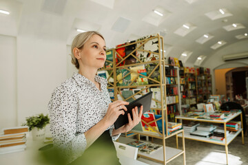 Thoughtful manager with digital computer in bookstore