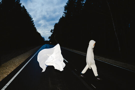 White cloth flying and boy walking on road at dusk