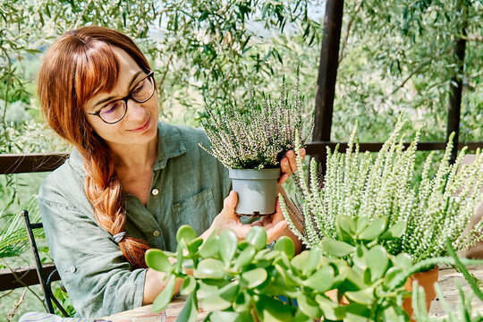 Smiling redhead woman holding Calluna vulgaris plant