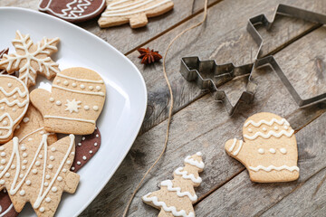 Plate with tasty Christmas cookies and cutters on wooden table, closeup
