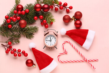 Alarm clock and Santa hats, Christmas tree branches with balls on pink background