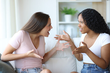 Angry interracial friends arguing at home