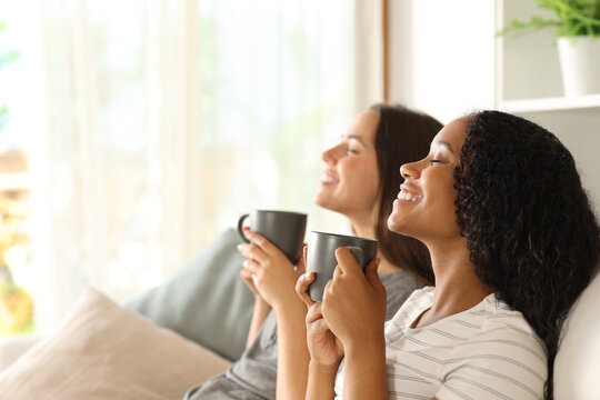 Happy interracial couple drinking and relaxing at home - Powered by Adobe