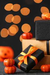 Gift boxes with pumpkins for Halloween celebration on grunge black table against blurred lights