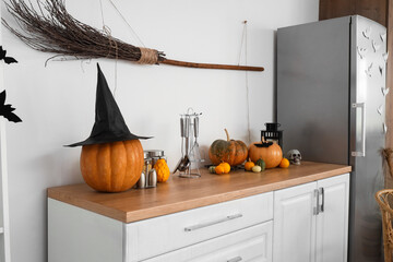 Interior of light kitchen decorated for Halloween with white counters and witch broom