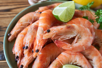 Boiled shrimps with lime on wooden table, closeup