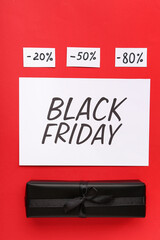 Naklejka premium Greeting card with text BLACK FRIDAY, gift box and discount tags on red background