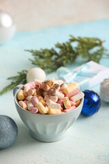 Cup of hot cocoa with marshmallows, Christmas balls and gift box on light blue table