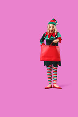 Shocked young woman dressed as elf with shopping bag on purple background