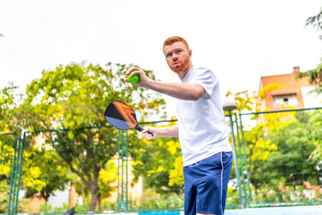 Man serving playing pickelball in an outdoor urban court