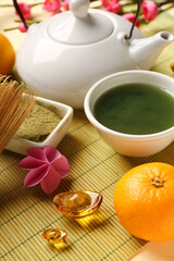 Teapot with matcha tea, mandarins and sakura on light background. Japanese New Year celebration