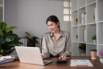 Fototapeta premium Businesswoman Working on Laptop in Modern Office with Plants and Documents on Desk