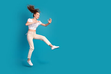 Obraz premium Full size photo of pretty young girl fighter kicking empty space wear trendy white outfit isolated on blue color background