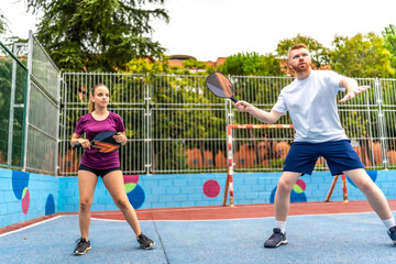 Friends playing pickelball in a blue colorful outdoor pitch