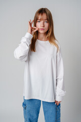 A young woman holding her finger to her lips, signaling silence in a minimalist studio