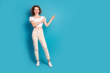 Full length photo of lovely young lady point empty space dressed stylish white garment isolated on blue color background