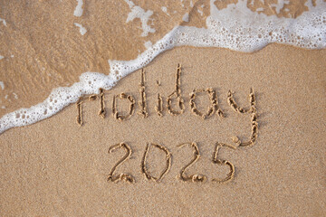 The inscription 2025 on the sand by the sea. Happy New Year.